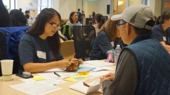 Volunteer helps someone apply for citizenship at a workshop